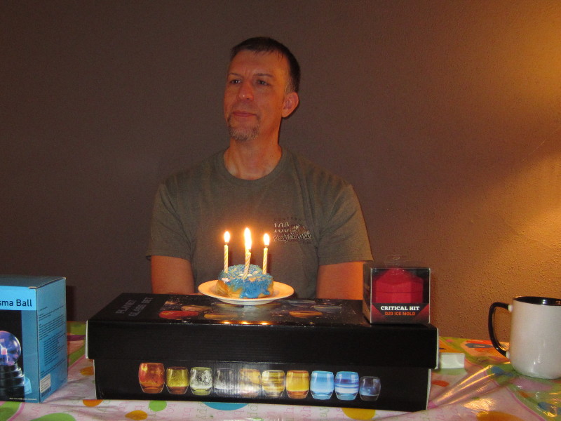Brian W Root sitting behind birthday cupcake and presents.